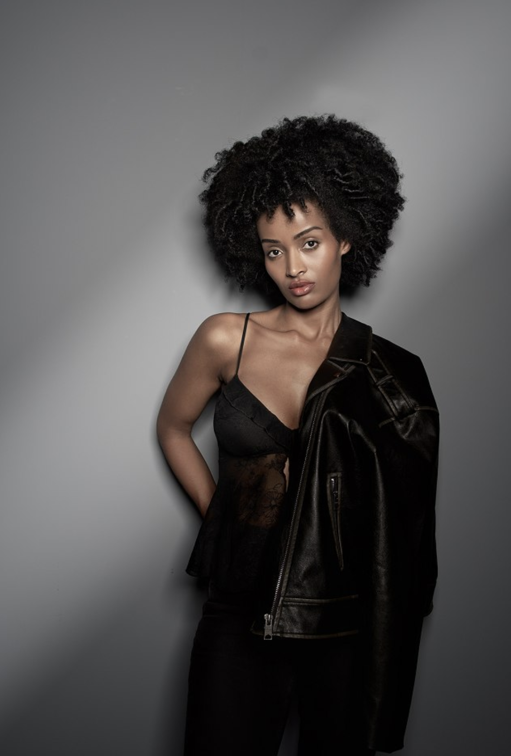 Mimi in a black leather jacket and lace top, studio portrait