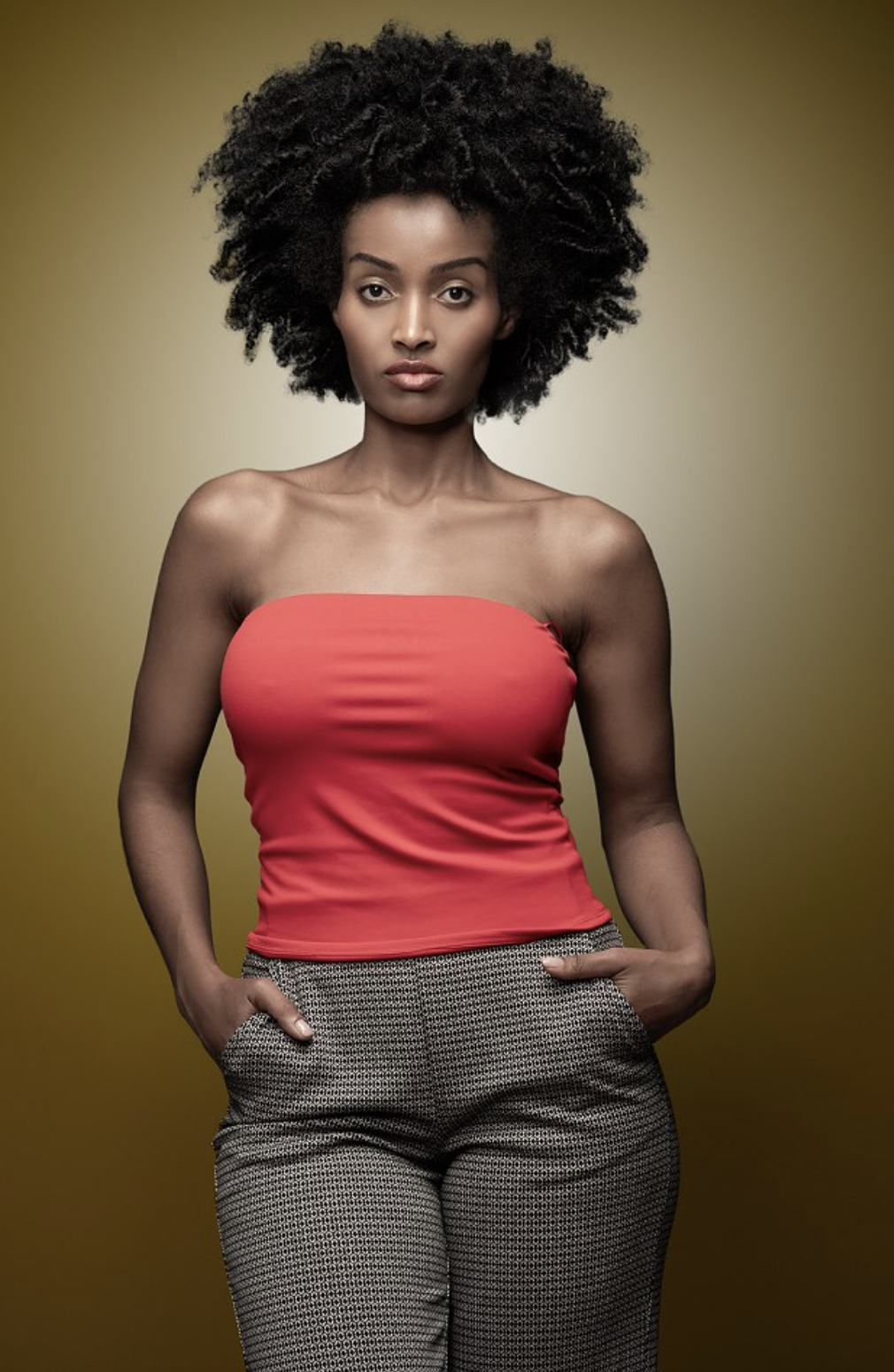 Mimi in a coral tube top and printed trousers against a warm olive backdrop